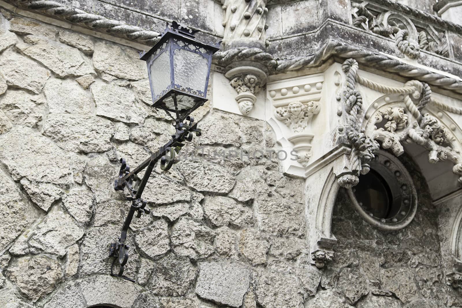 Old street lamp on a wall, detail of city lighting, electricity and light