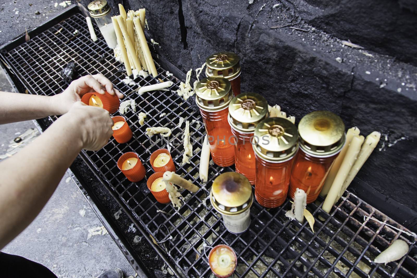 Light candles, detail of a person putting candles in a church