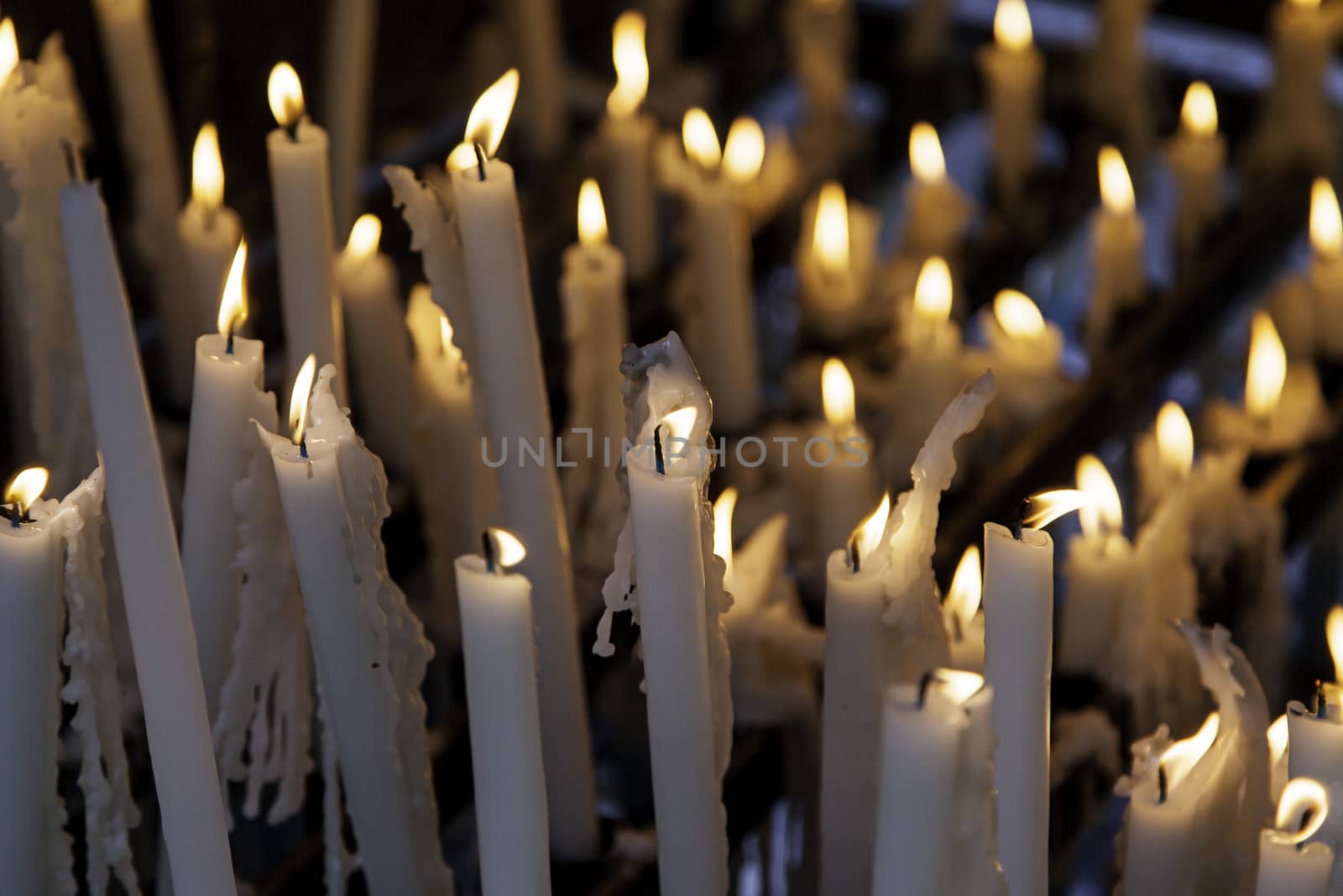 Candles lit at night, detail of an element of light, beliefs and faith, flame