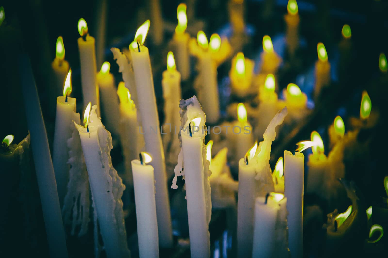 Candles lit at night, detail of an element of light, beliefs and faith, flame