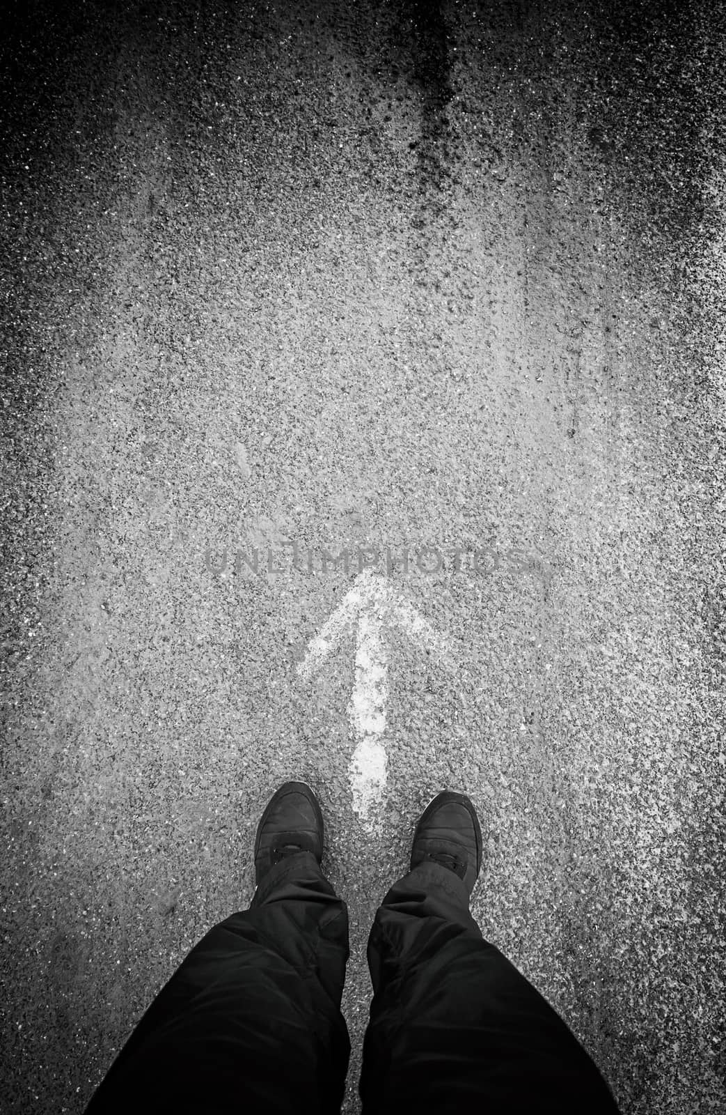 Feet in front of an arrow, detail of a direction arrow, sign