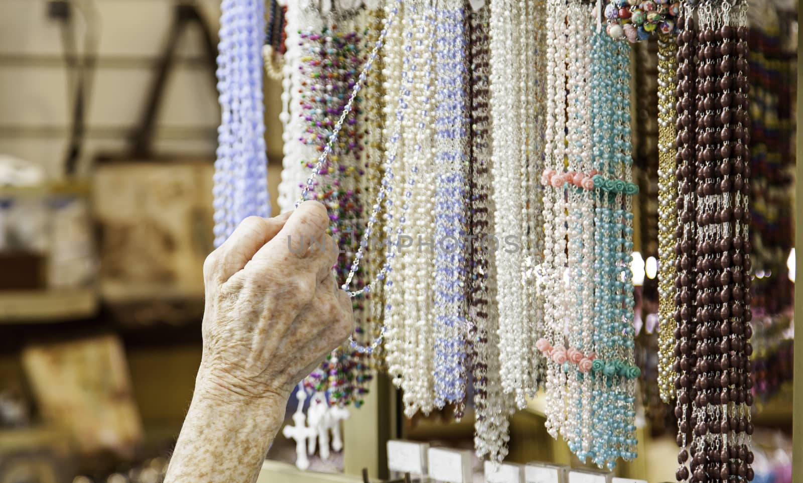 Elderly person choosing necklaces in a market, detail of shopping in the city