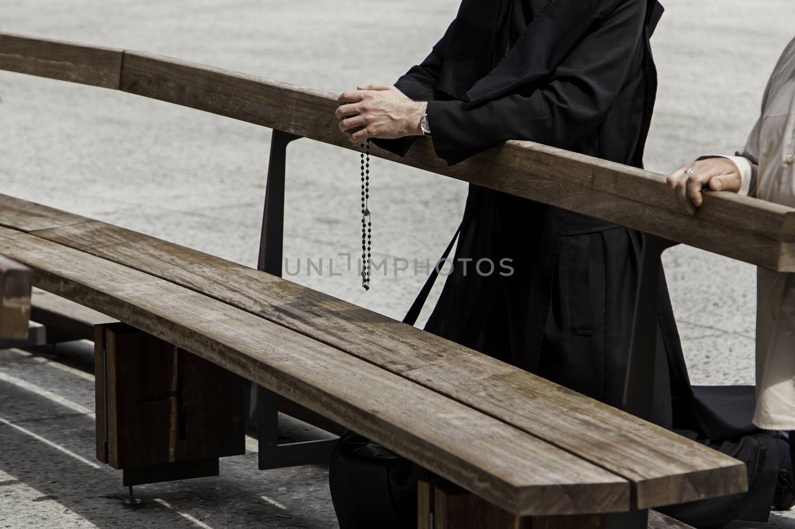 Hands of a priest with cross praying, detail of belief and Christian faith