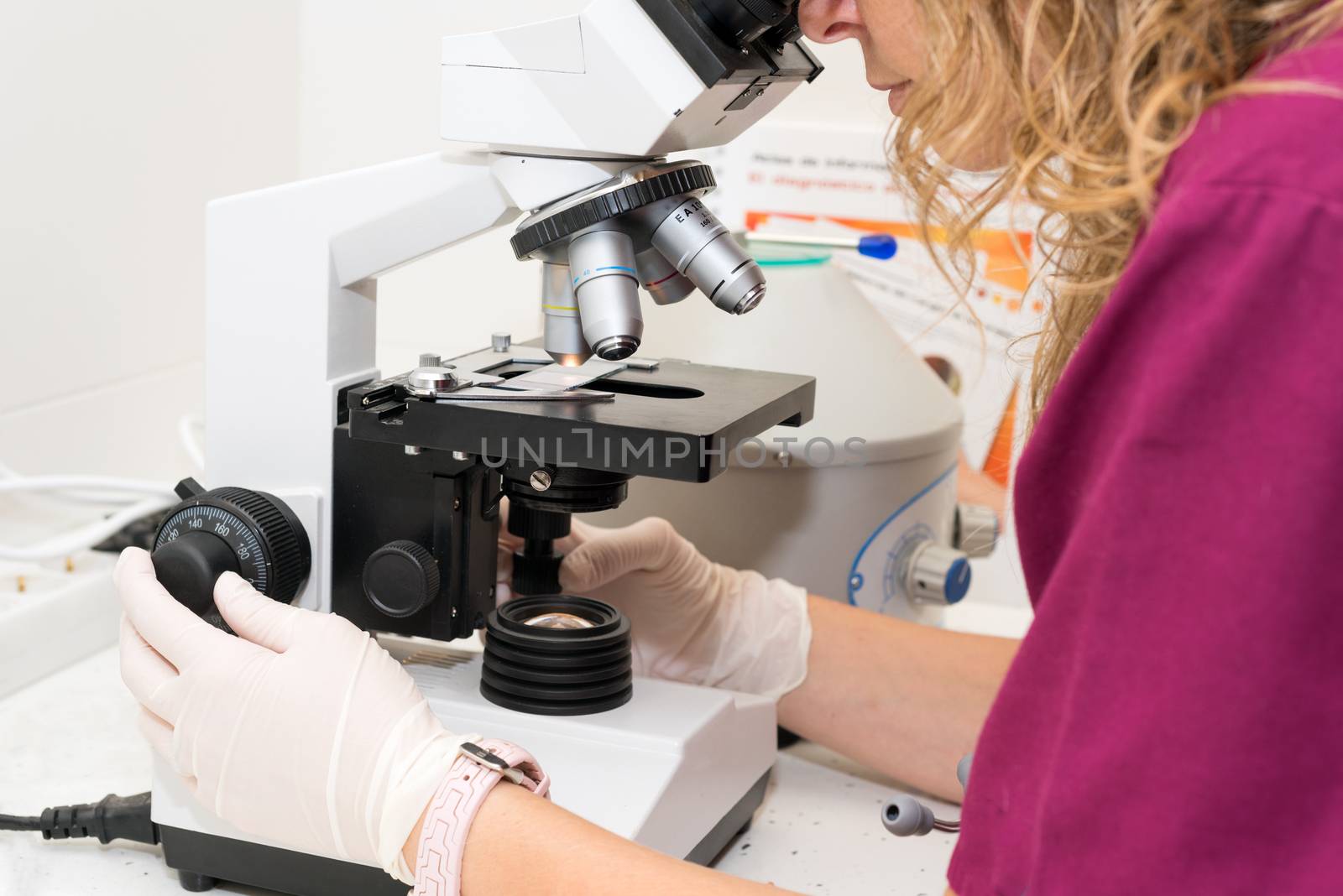 Young scientist looking through a microscope in a laboratory by HERRAEZ