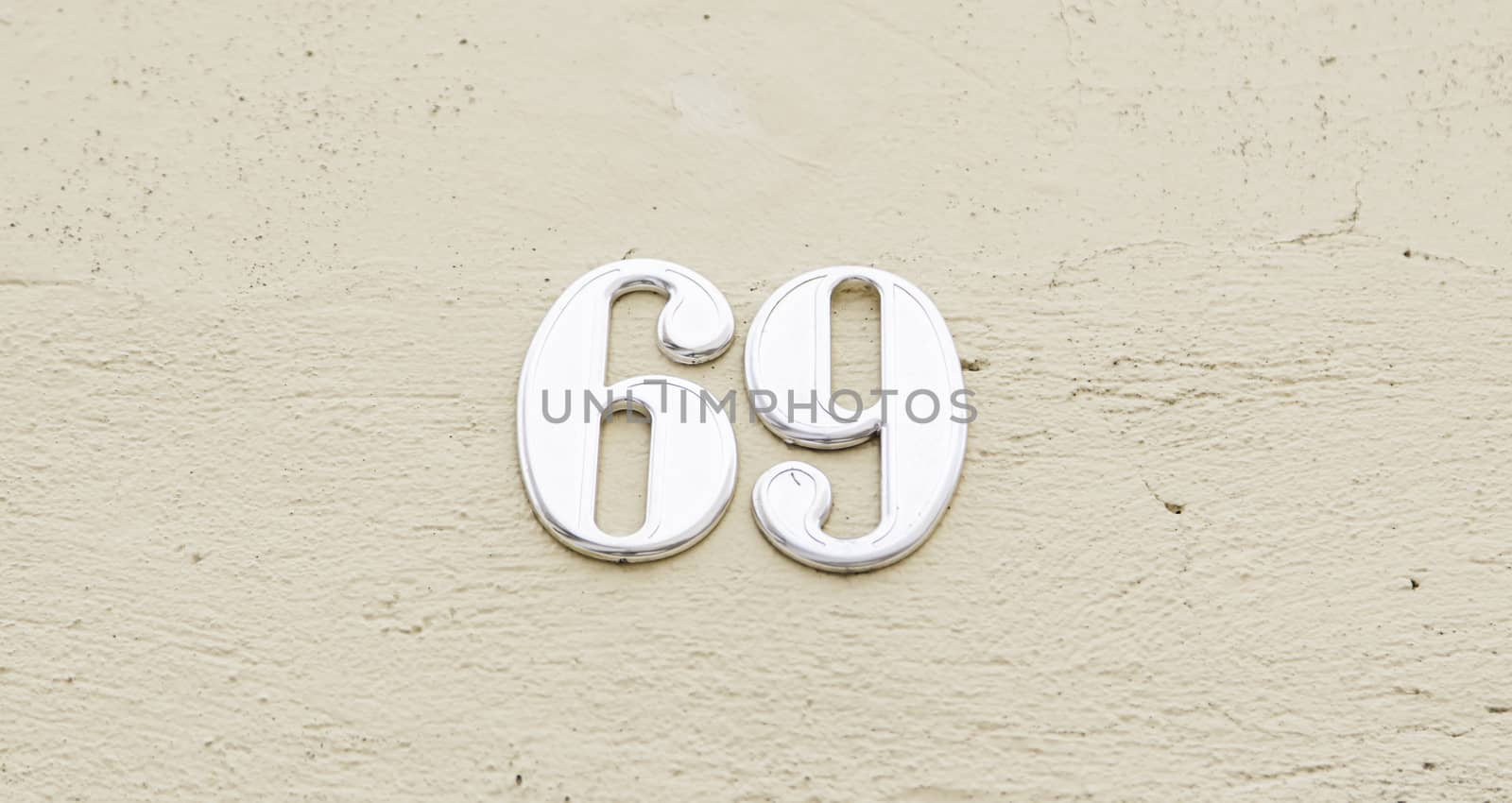 Number sixty nine on the wall of a house, detail of a number of information, odd number