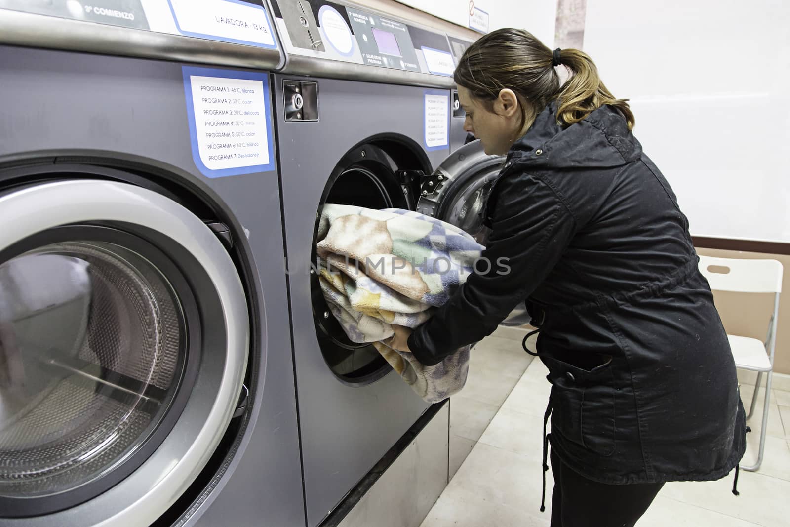 Young woman in a laundry, detail of person washing clothes, cleaning and hygiene
