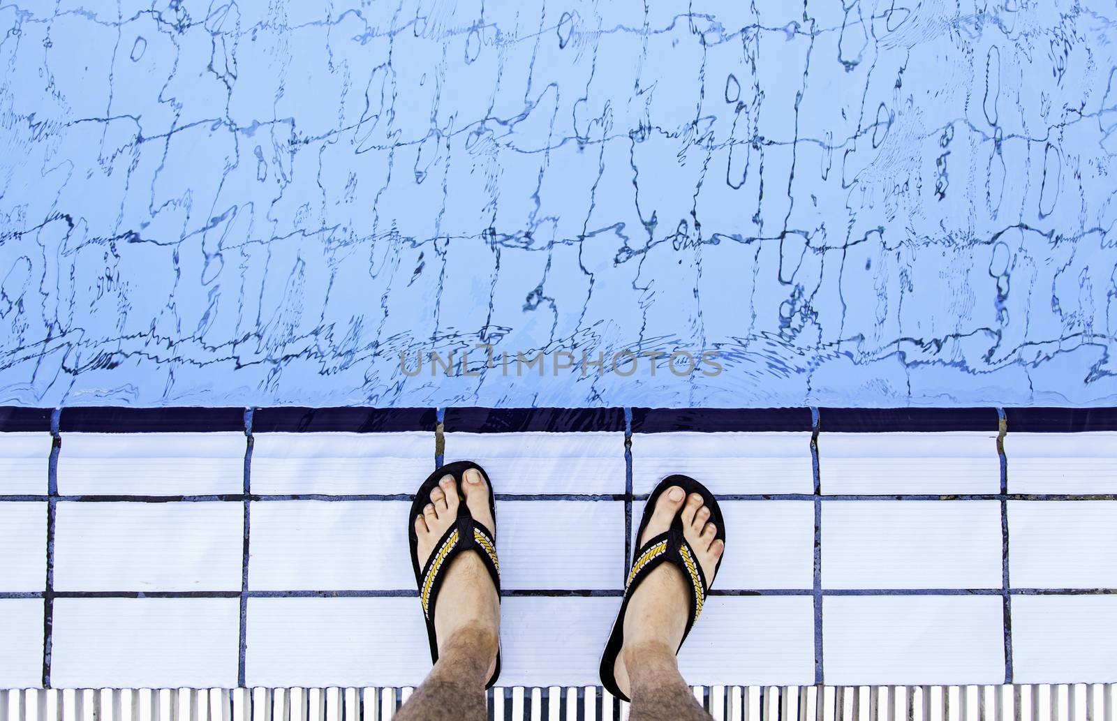 Man's feet in the water of a pool, detail of summer and refreshment, heat
