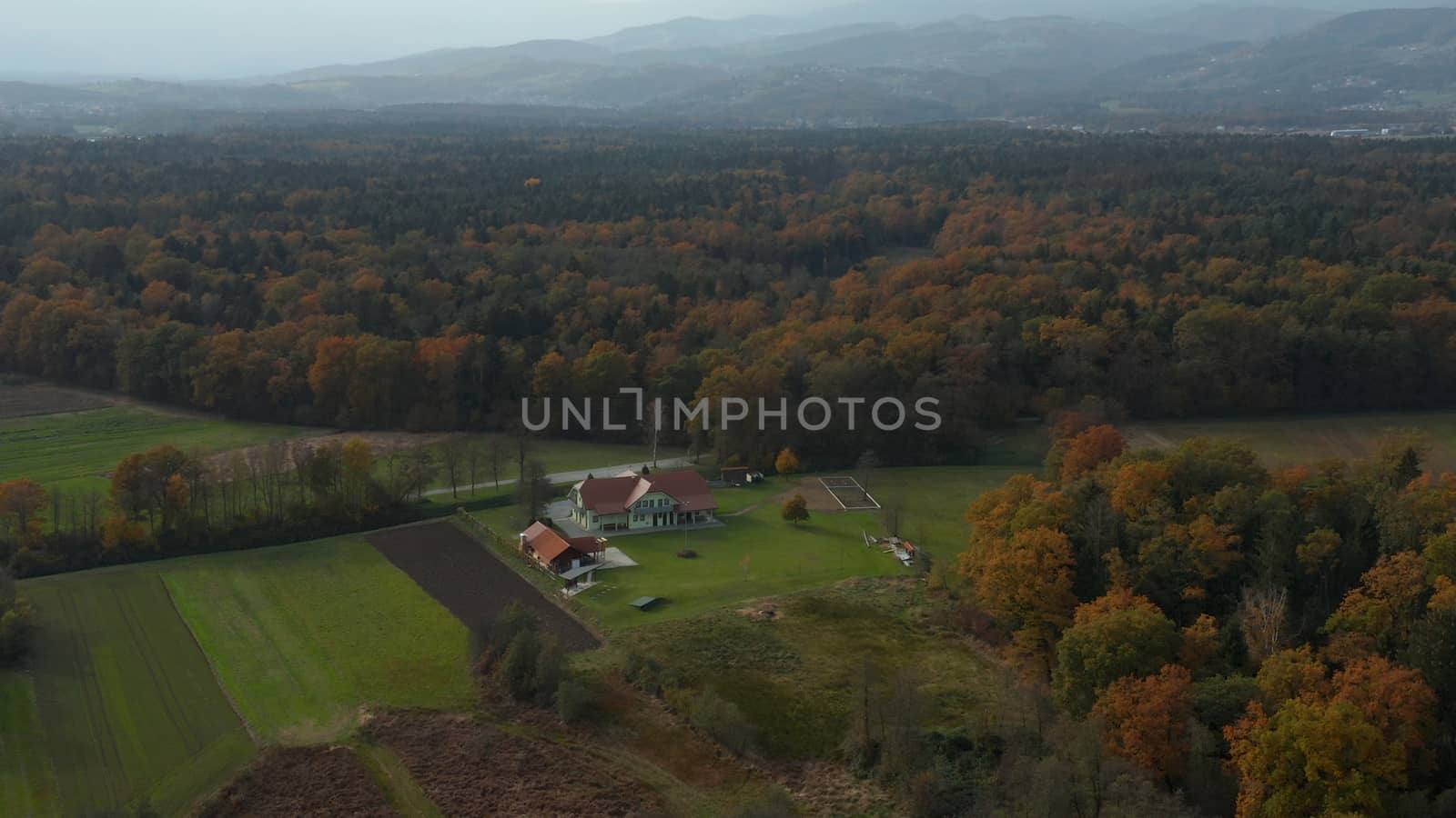 Aerial view of east Slovenia countryside with fields, forest and hedges, hedgerows dividing fields and meadows, Pohorje mountain in far background, traditional small farms agriculture