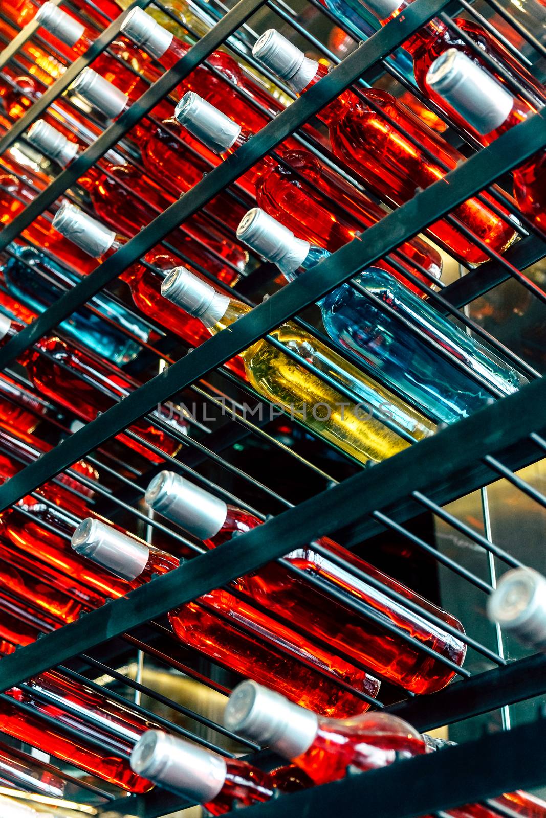 Rows of colourful wine bottles, Detail image of Metal rack with plenty of wine bottles composed in rows for decor.