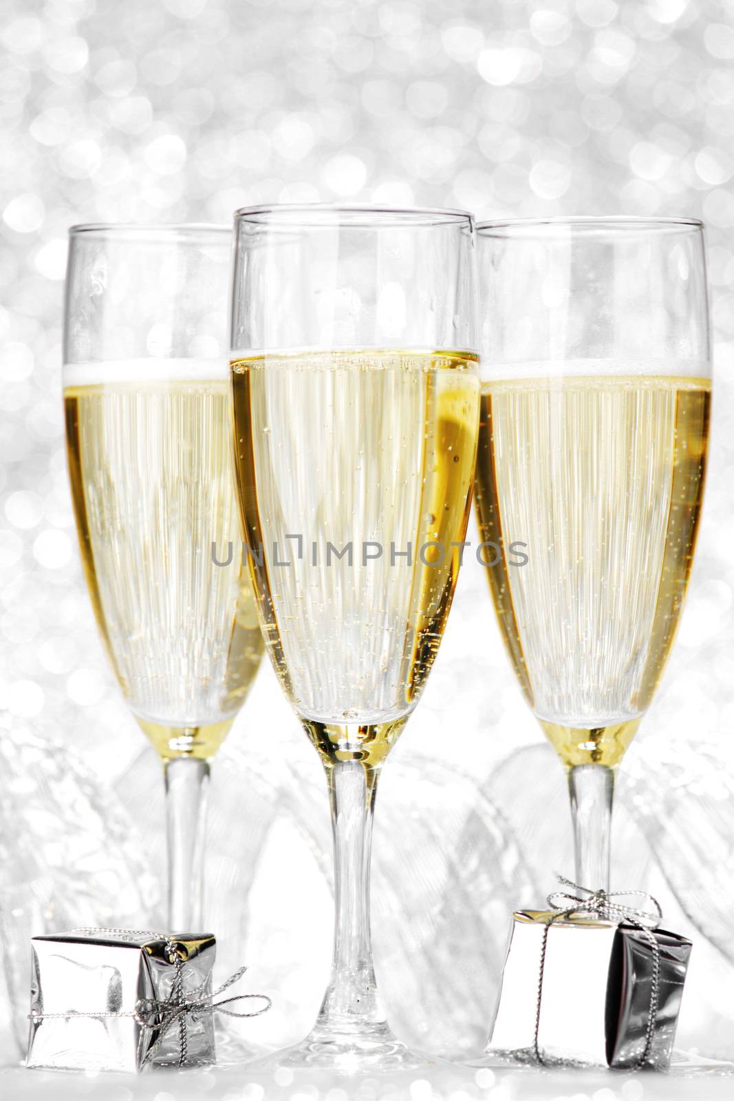 Glasses of champagne and christmas gifts on silver background