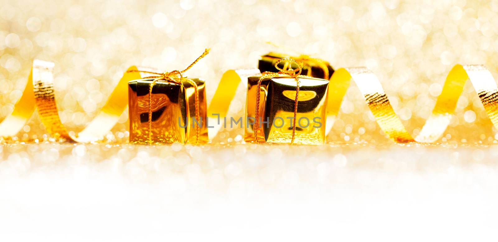 Decorative golden boxes with holiday gifts on shiny glitter background