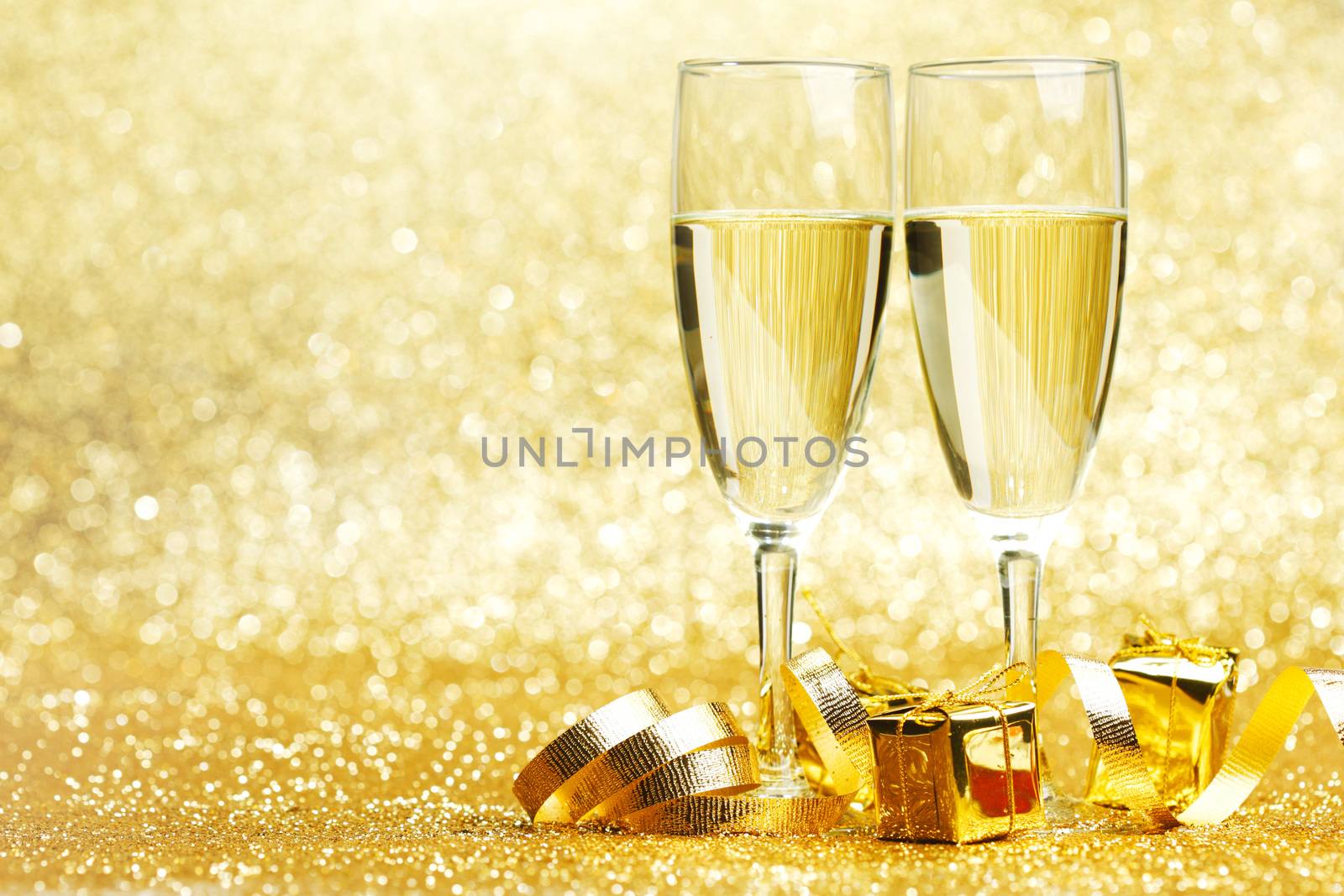Champagne glasses and gifts on glitters background