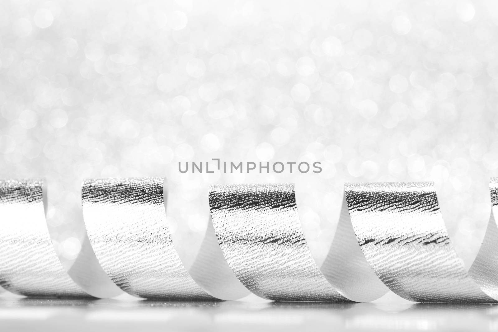 Shiny silver gift ribbon on bokeh background close-up