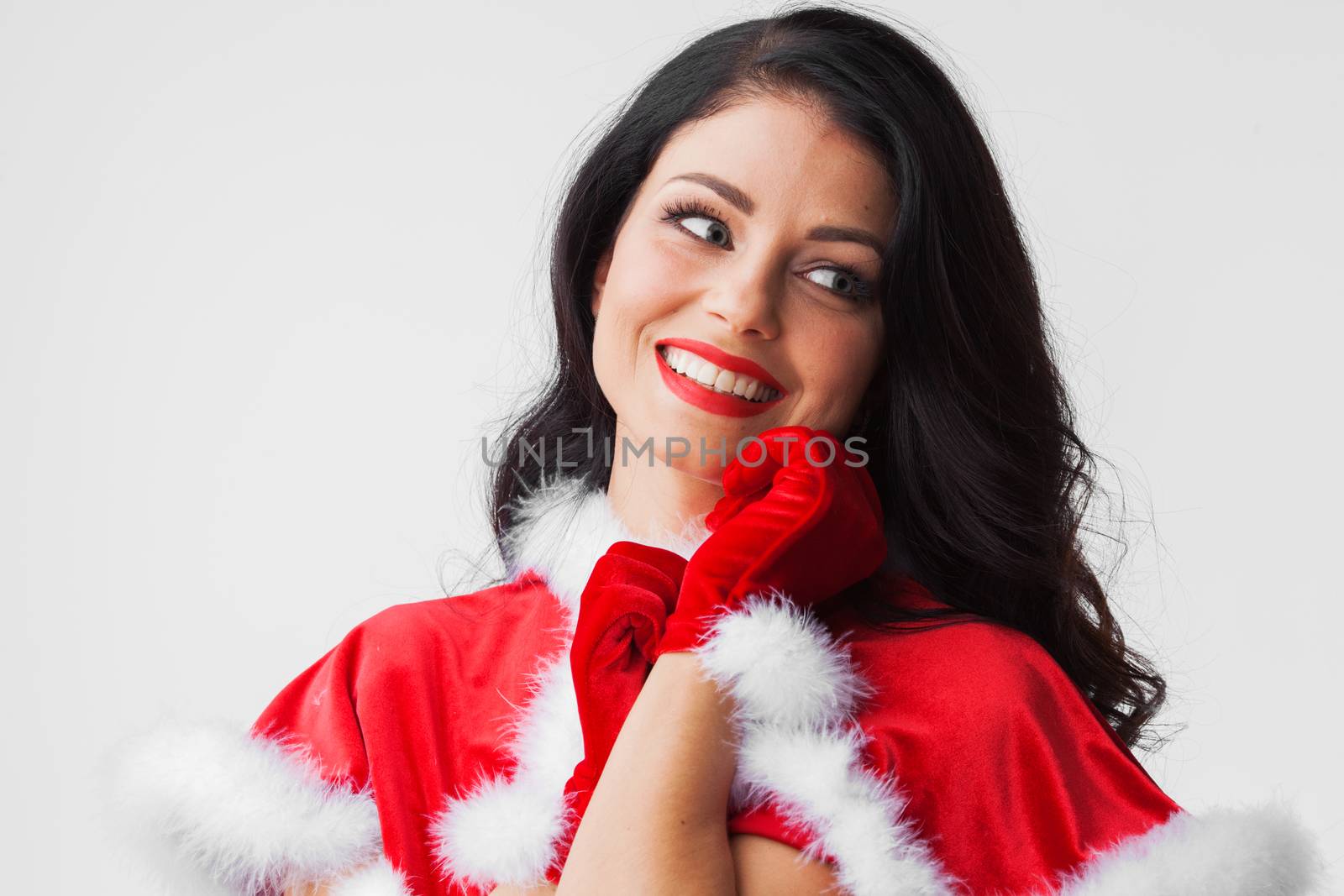 Pretty Pin-up style Santa girl in red clothes on gray background