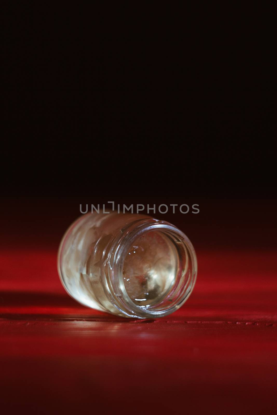 Honey in a glass jar close up on a black background on a red wooden table. pour honey with a stick honey dipper by yulaphotographer