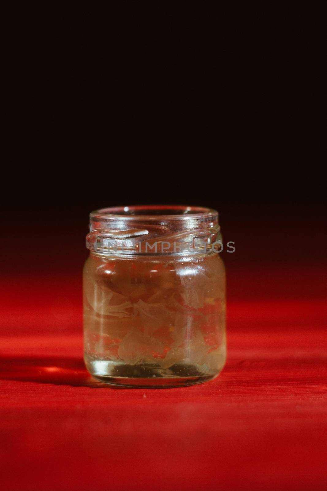 Honey in a glass jar close up on a black background on a red wooden table. pour honey with a stick honey dipper by yulaphotographer