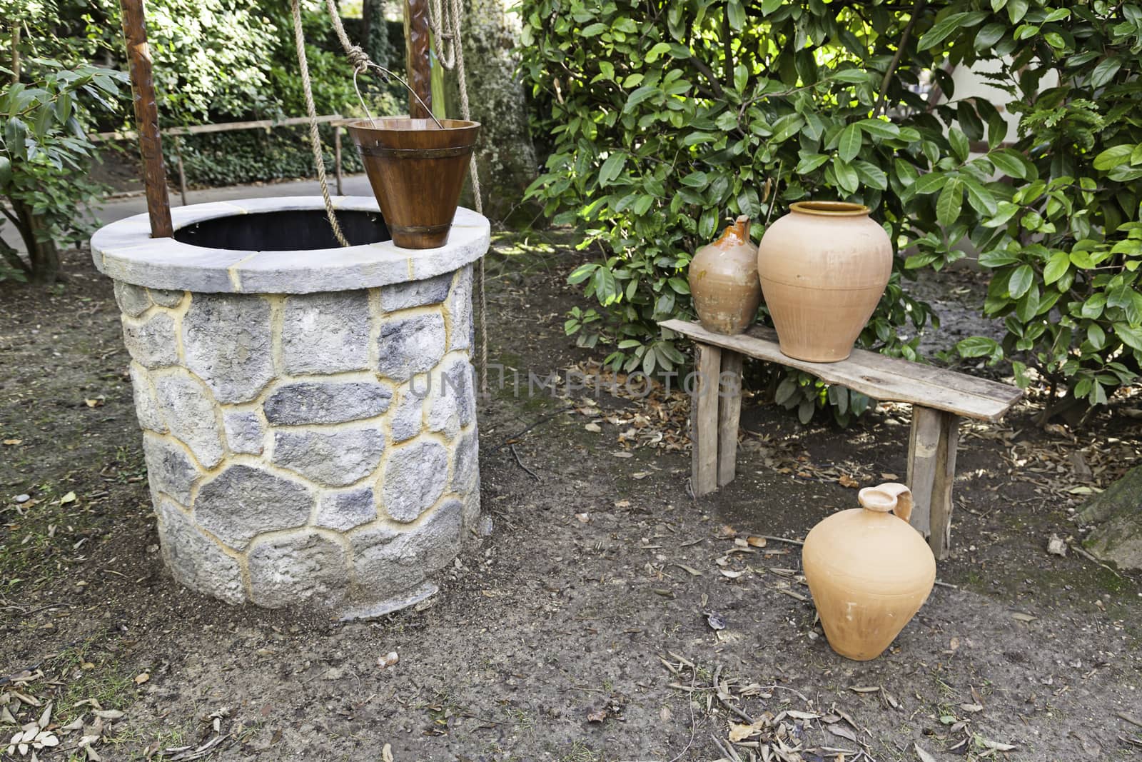 Well in a garden detail of a rural garden with a water well and jugs