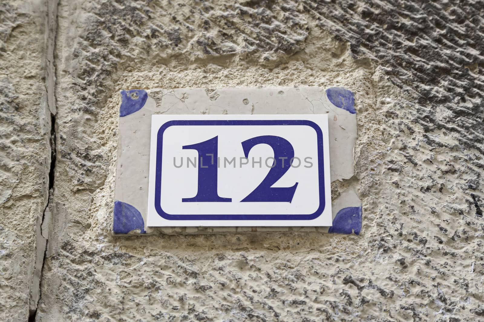 Number twelve on a plate on a wall, detail of a number of information in a house in the city
