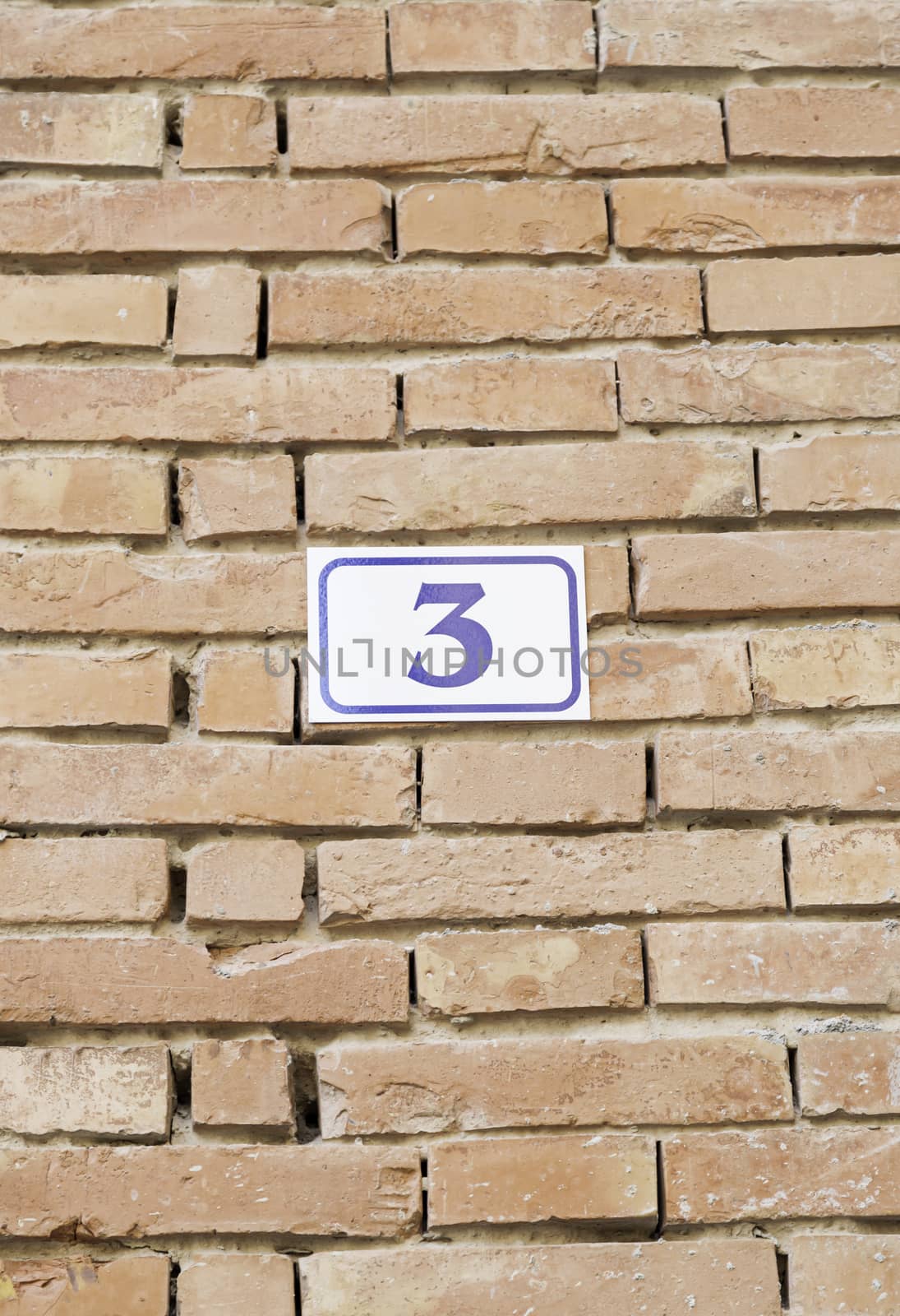 Number three on a brick wall, detail of a number of information in city, textured background