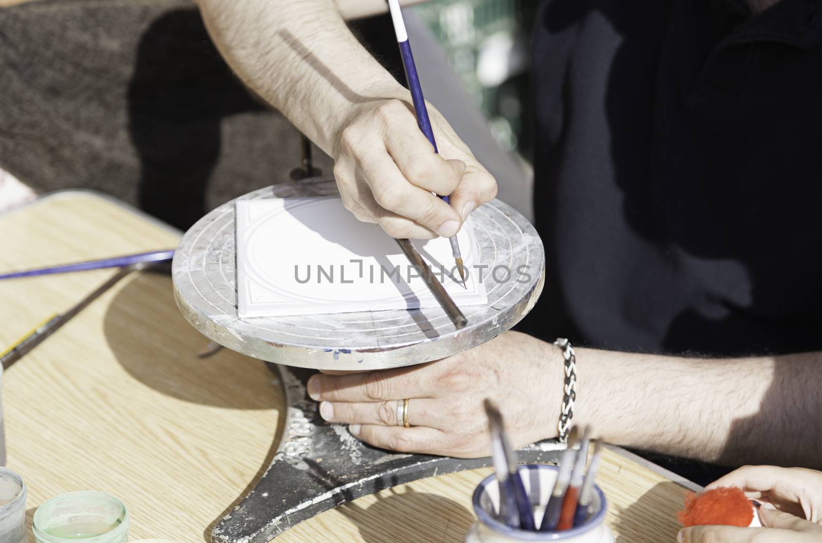Hand painting a plate, detail of a craftsman decorating a ceramic dish, traditional art