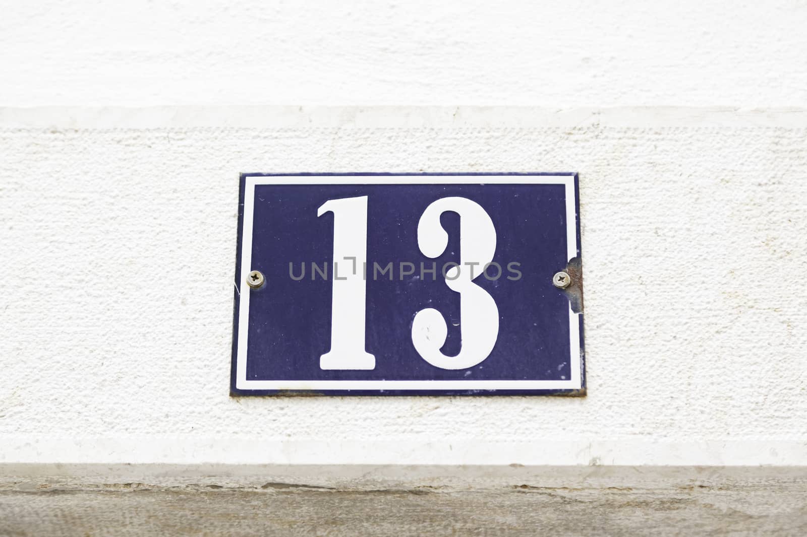 Number thirteen on a wall in a house, detail of a wall with a figure on a plate 