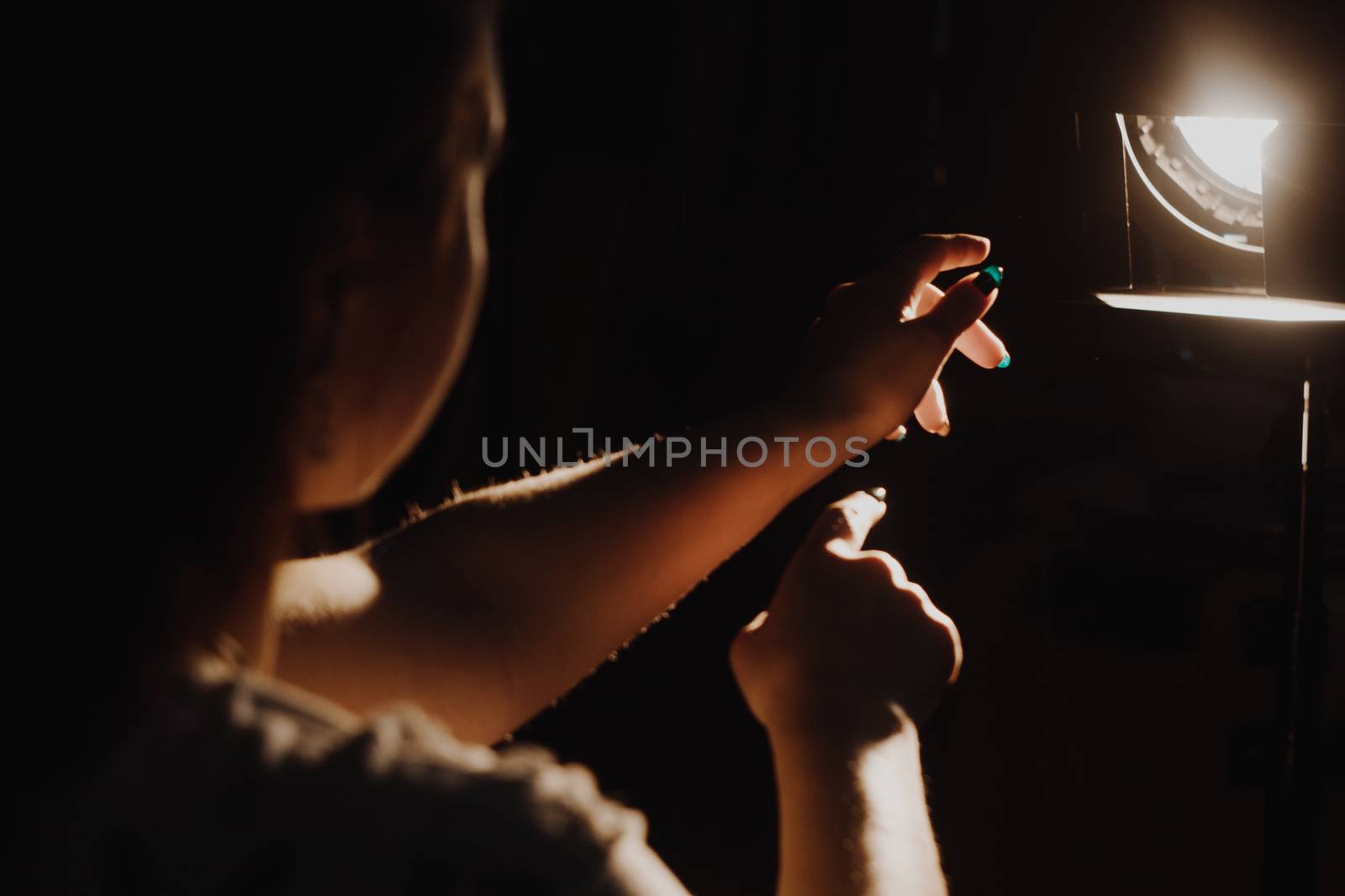 girl reaching for the light of the lantern, wooman in a dark room. illuminated hands with spotlight