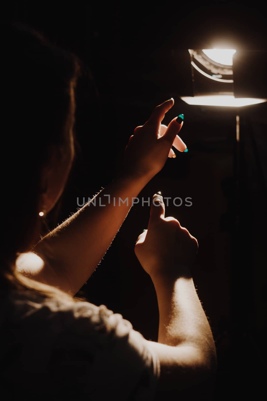 girl reaching for the light of the lantern, wooman in a dark room. illuminated hands by yulaphotographer