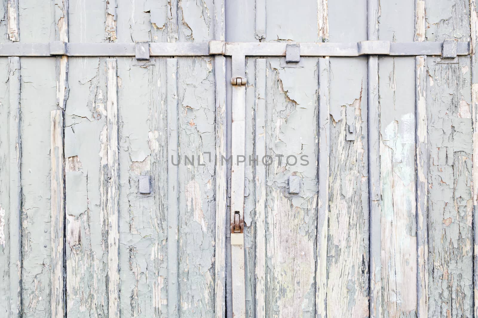 Abandoned gray wooden door, detail of an old door damaged on the street