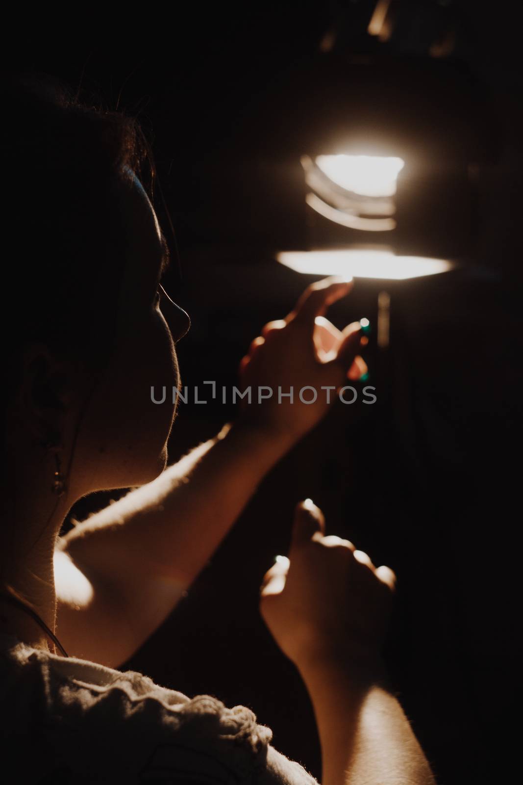 girl reaching for the light of the lantern, wooman in a dark room. illuminated hands with spotlight