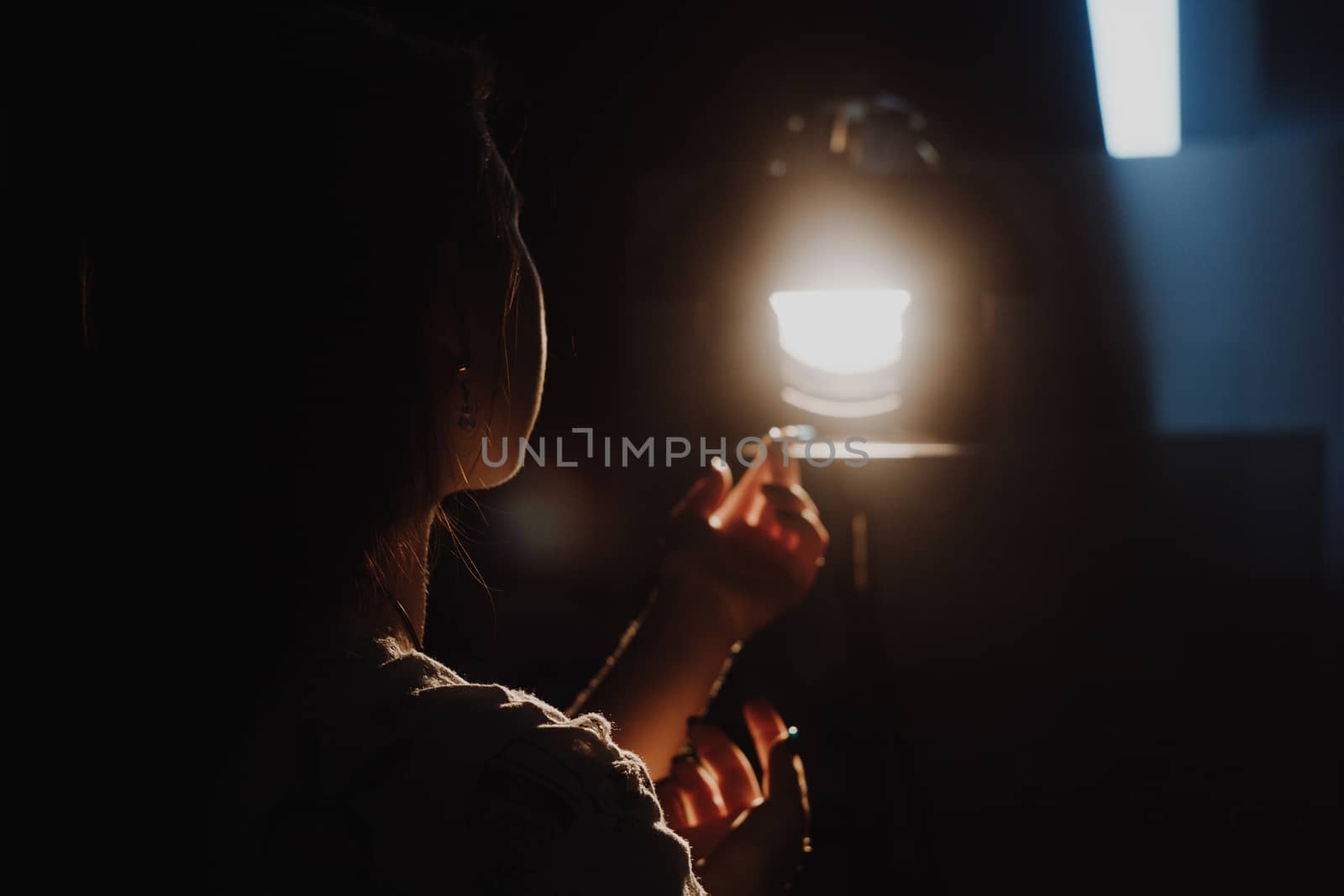 girl reaching for the light of the lantern, wooman in a dark room. illuminated hands with spotlight