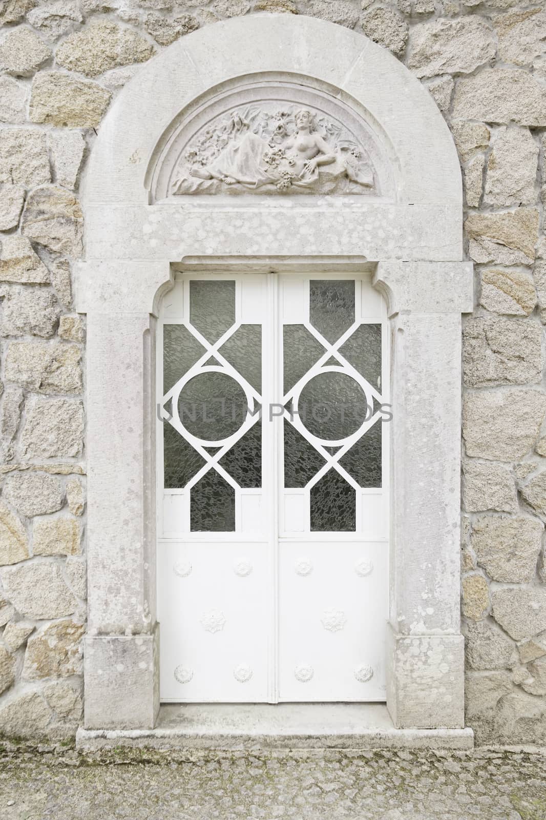 Old closed white door, detail of a wall with a door protection and decoration