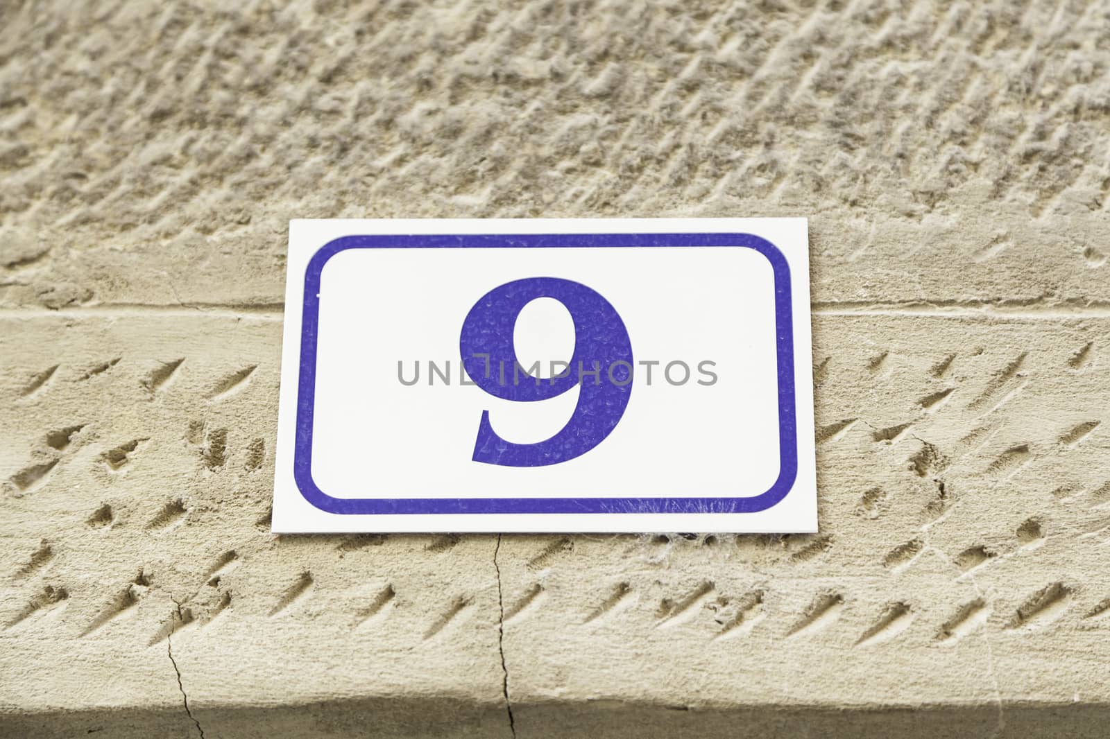 Number nine on a wall, detail of a number of information on a wall of a house, odd number