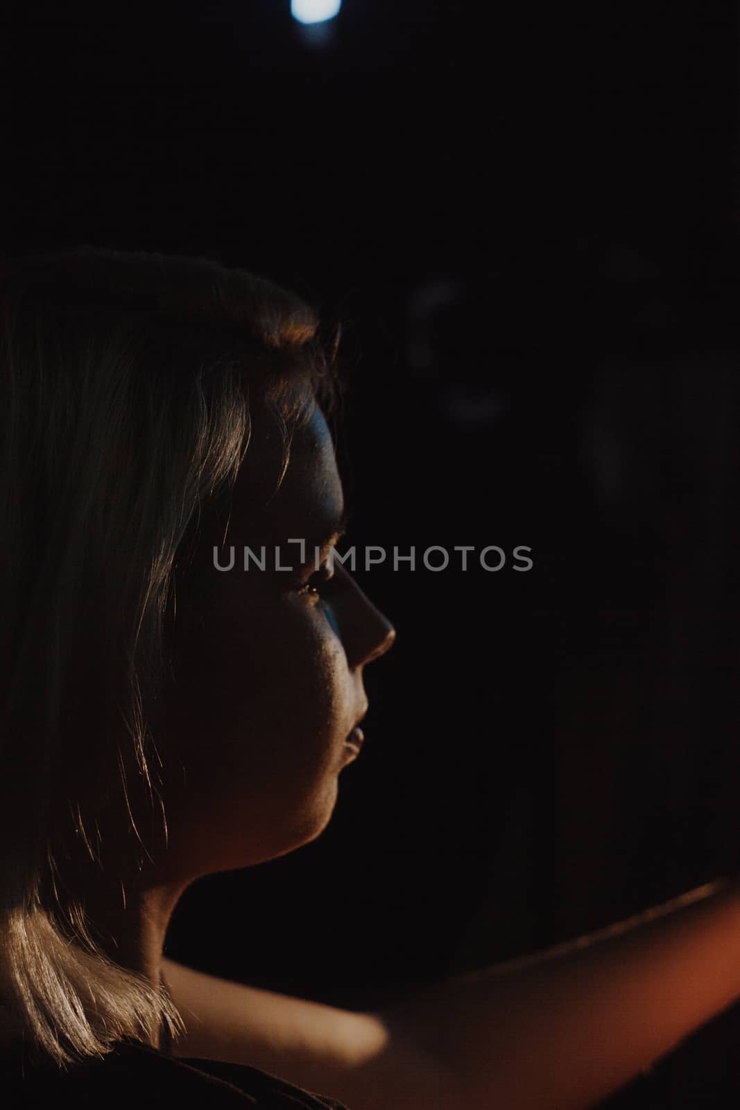 girl reaching for the light of the lantern, wooman in a dark room. illuminated hands with spotlight