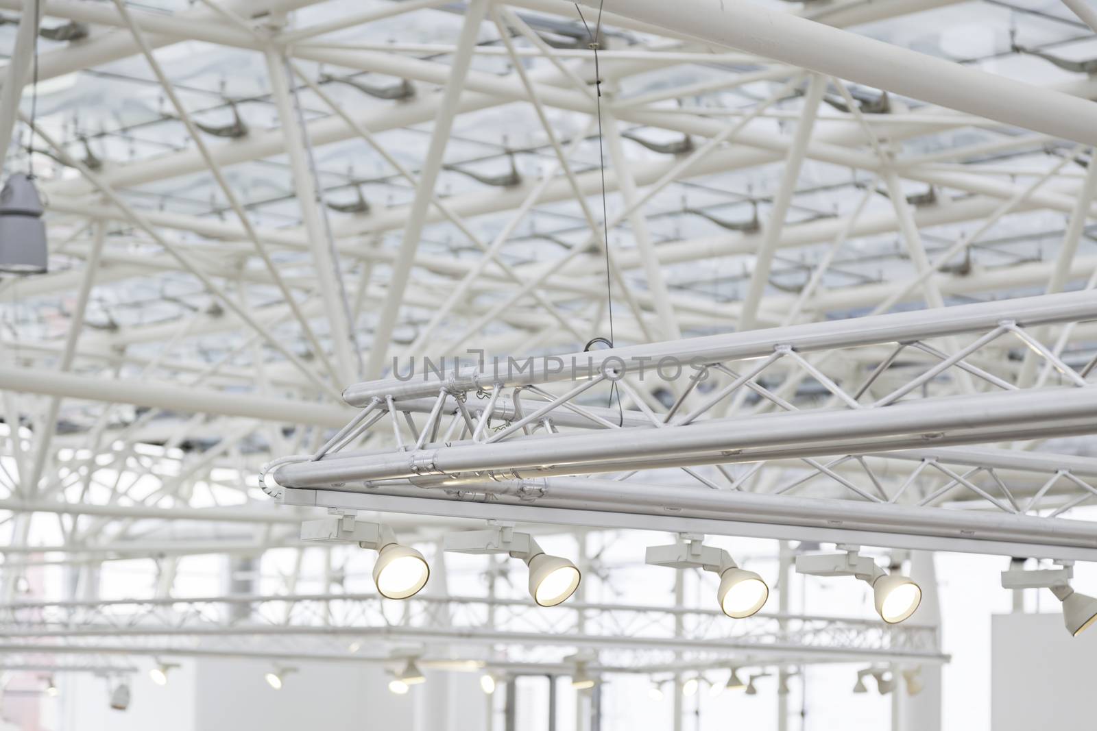 Focuses on an interior roof detail of an electric lighting on a ceiling in an industrial building