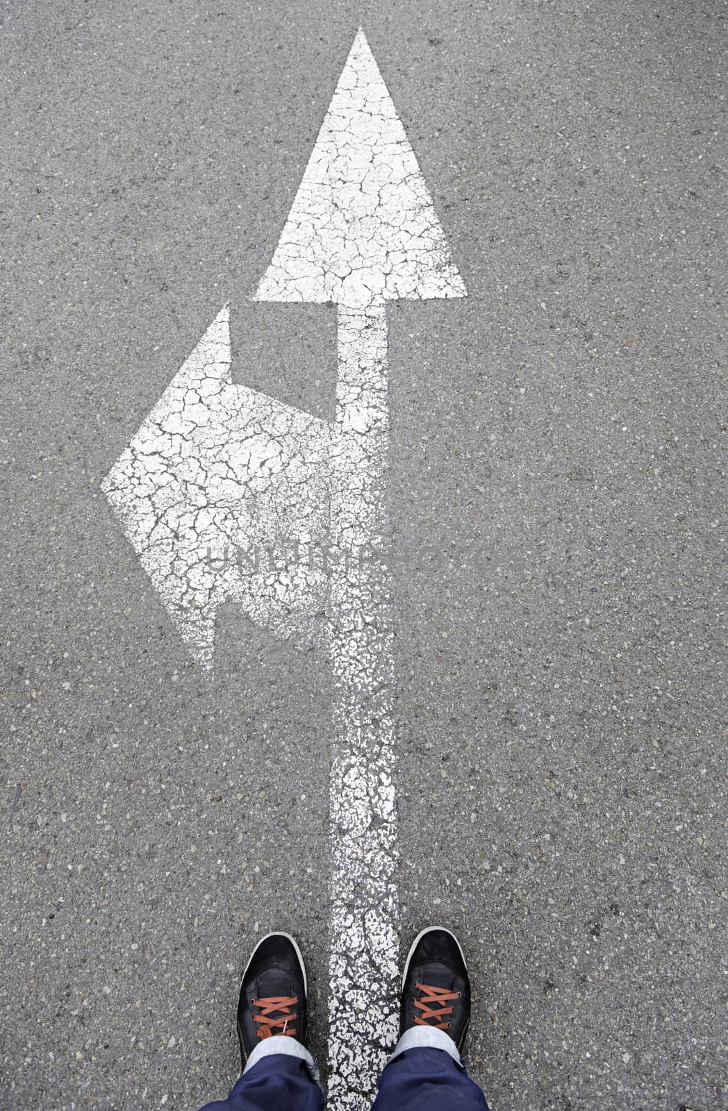 Directional arrow on the asphalt with a few feet, detail of a direction sign painted on the asphalt road safety