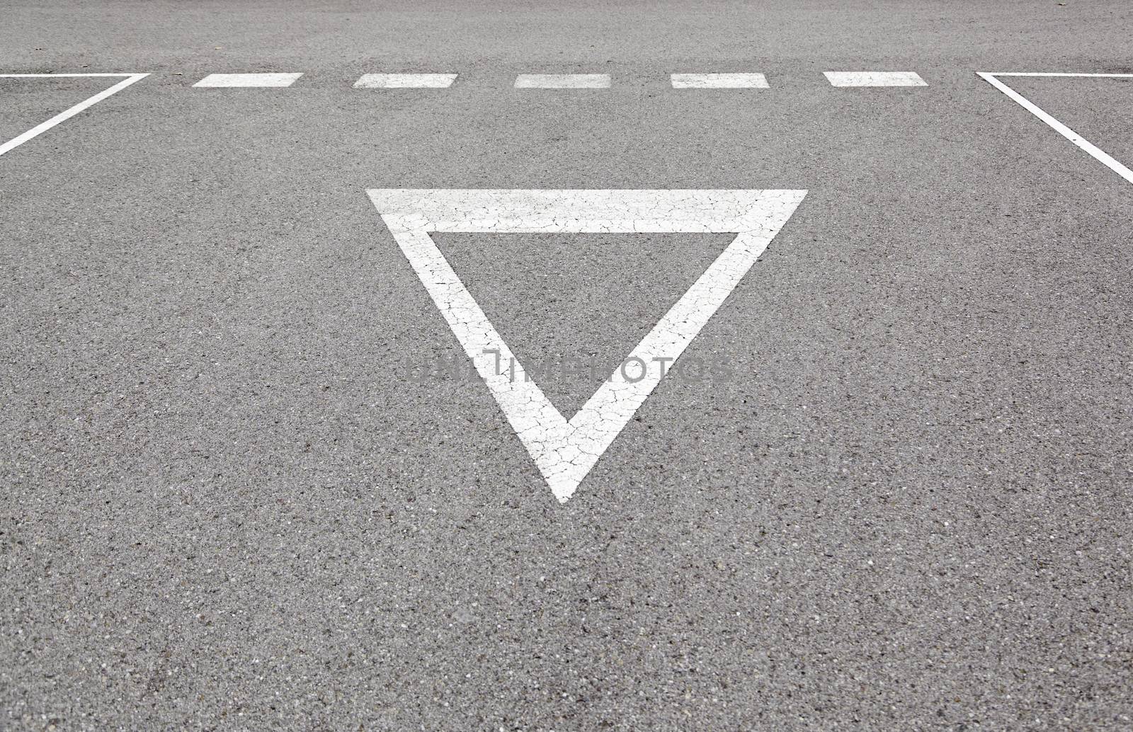 Give way sign on asphalt, detail of a traffic signal at the ciduad, information and road safety