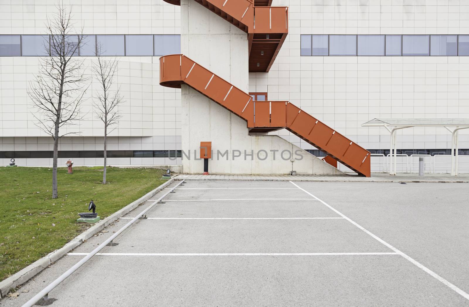 Building facade with red staircase, detail of a wall in the parking lot outside, architecture