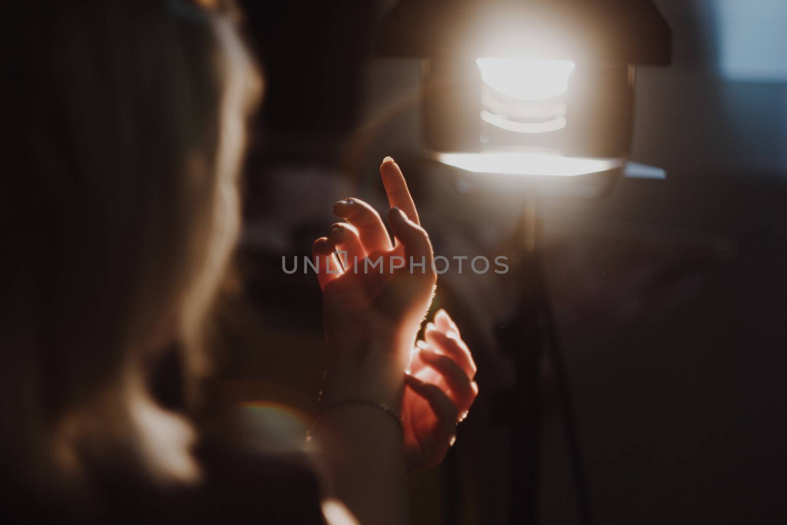 girl reaching for the light of the lantern, wooman in a dark room. illuminated hands with spotlight