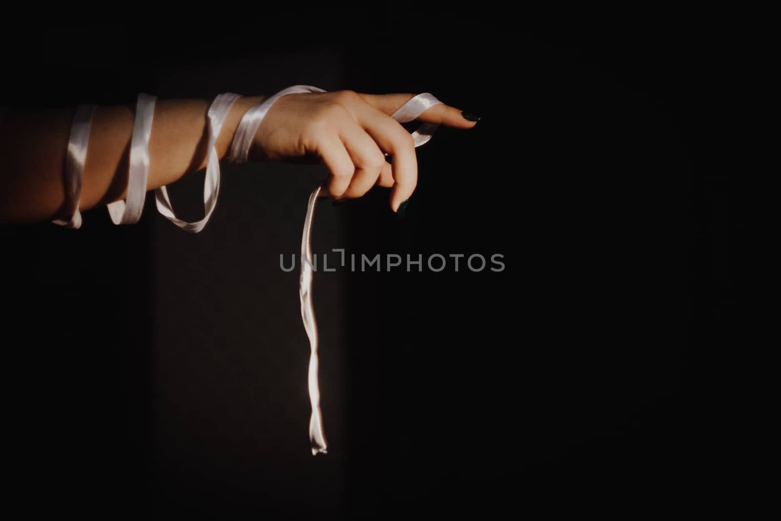 tied hands with ribbon isolated on black background highlighted with light