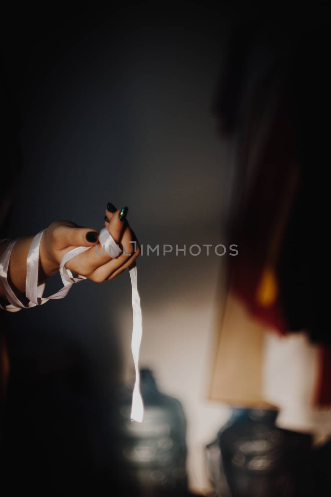 tied hands with white ribbon isolated on black background highlighted with light by yulaphotographer