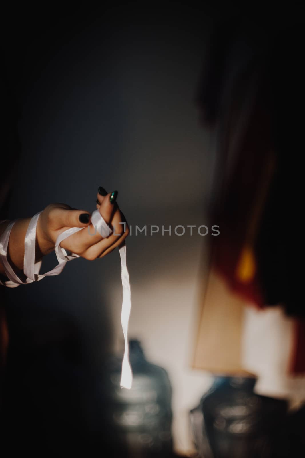 tied hands with ribbon isolated on black background highlighted with light