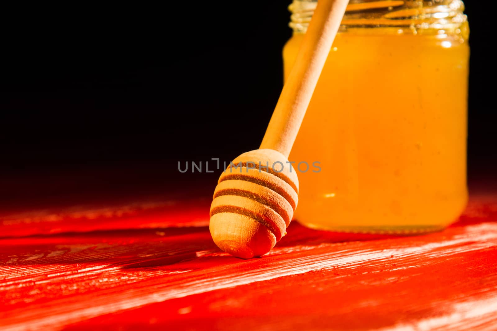 Honey with dipper on wooden background with the the play of light and shadow by yulaphotographer