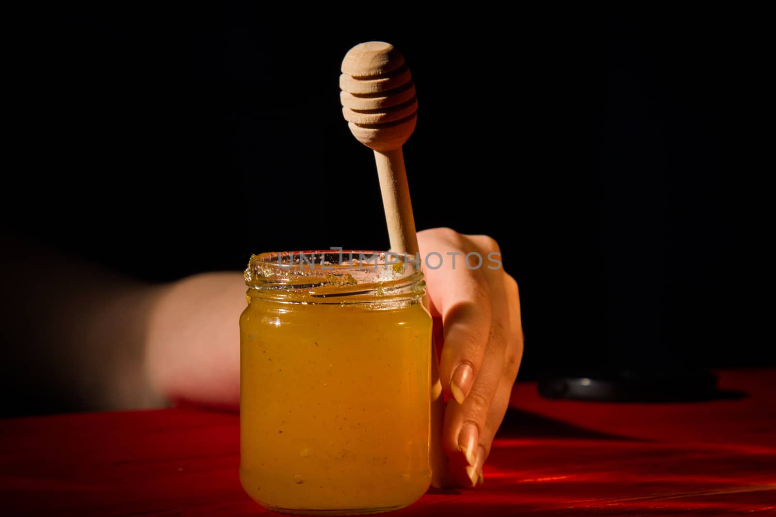 Honey with dipper on wooden background with the the play of light and shadow by yulaphotographer