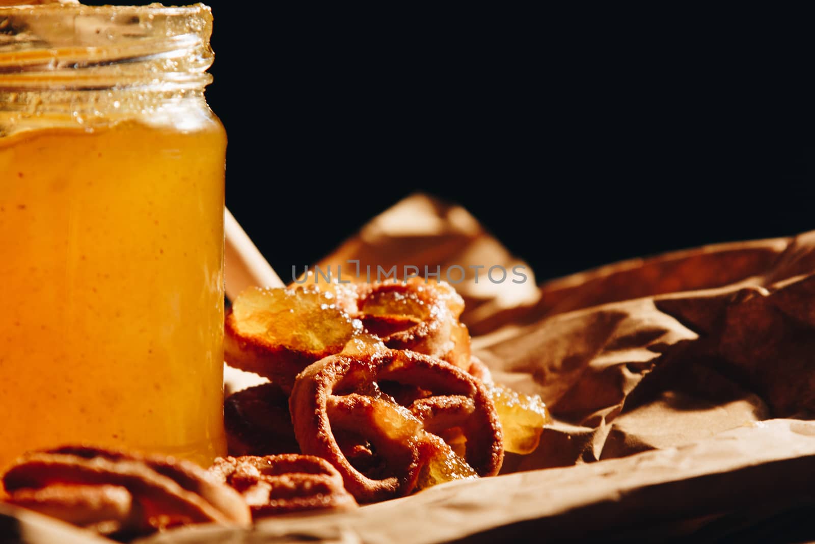 Honey with wooden honey dipper paper napkin and fruits on wooden table close up by yulaphotographer