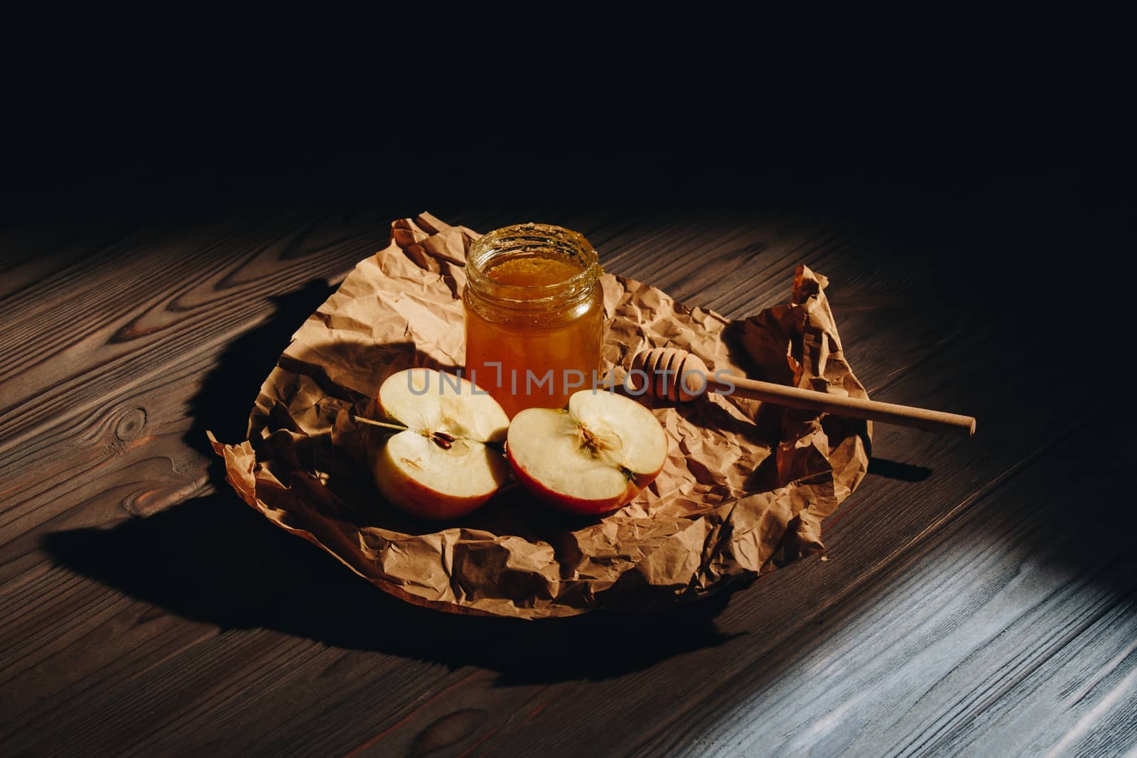 Honey with wooden honey dipper paper napkin and fruits on wooden table close up by yulaphotographer