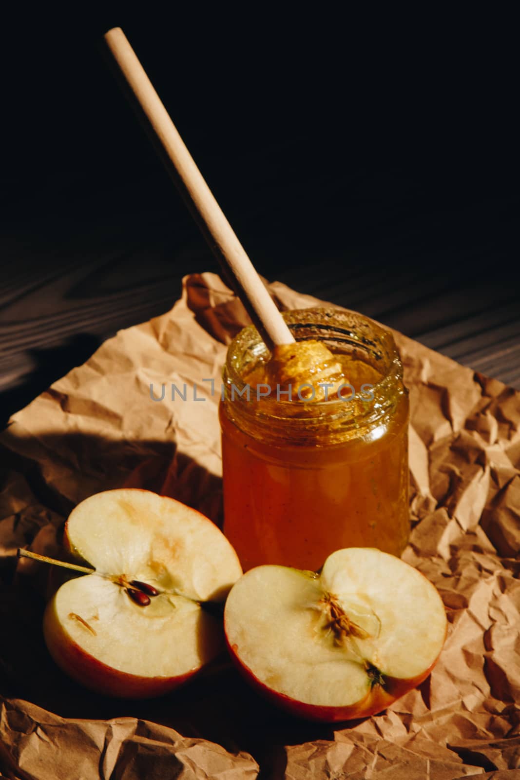 Honey with wooden honey dipper and fruits on wooden table close up