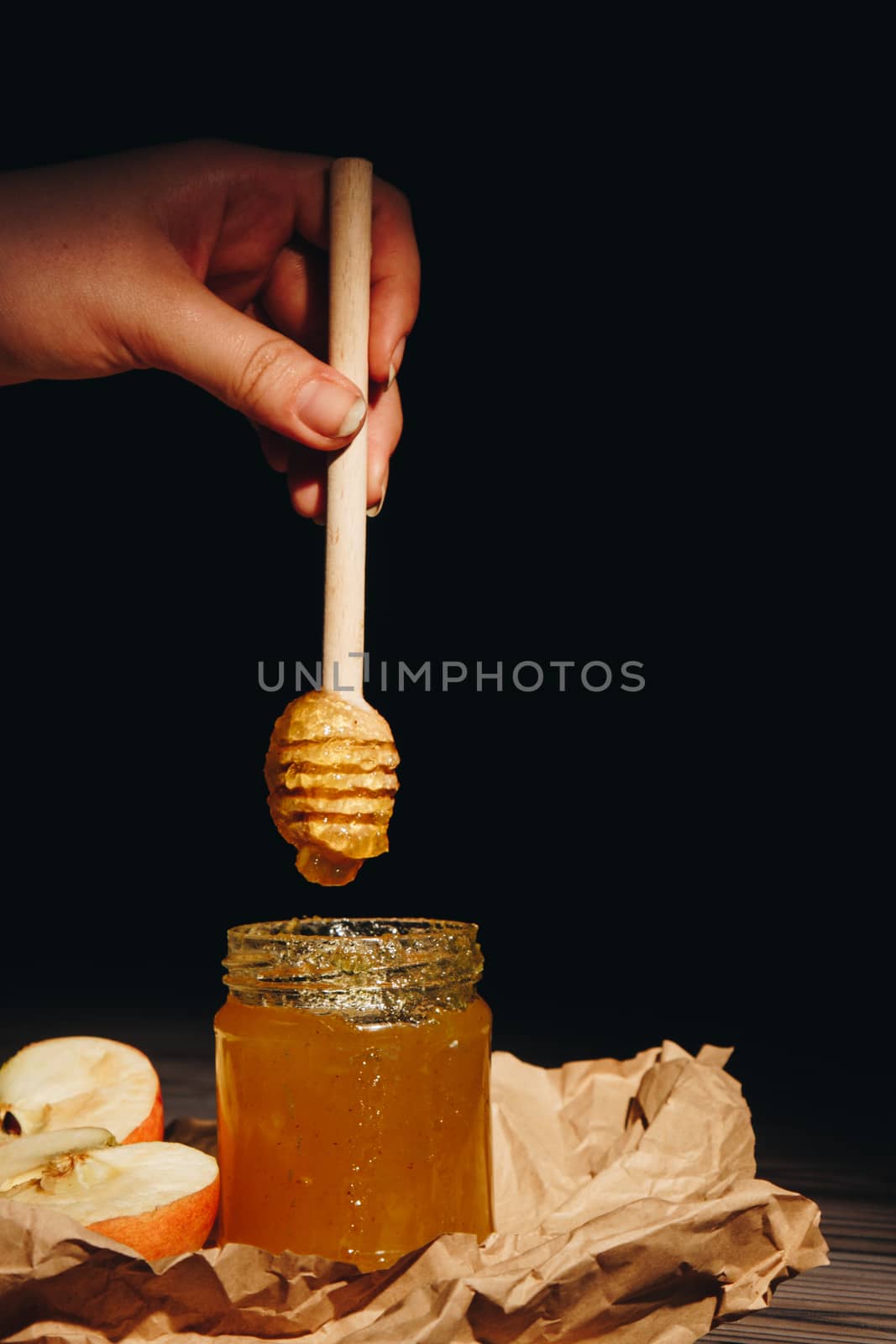 Honey with wooden honey dipper paper napkin and fruits on wooden table close up by yulaphotographer