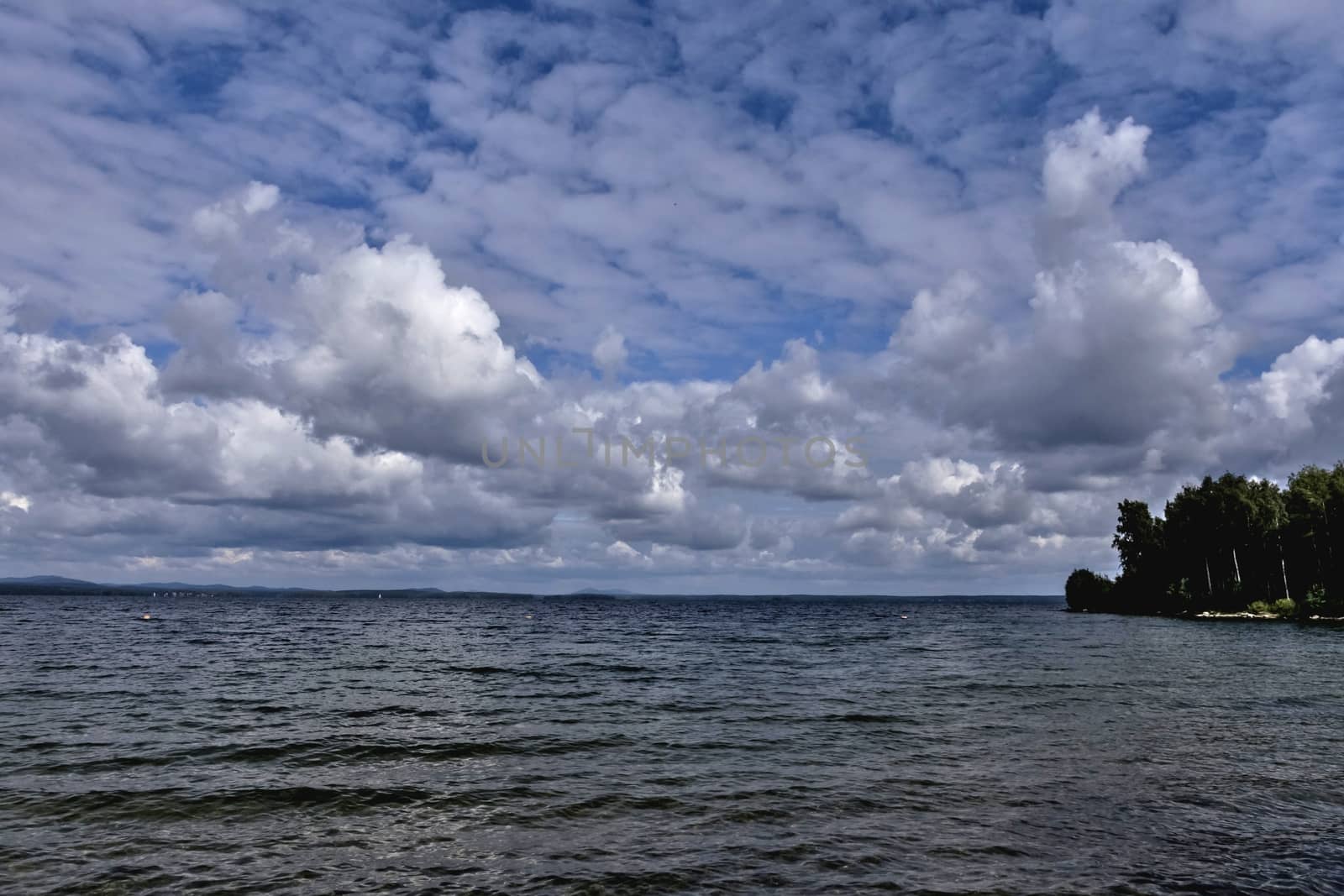 blue sky with powerful cumulonimbus clouds over the lake