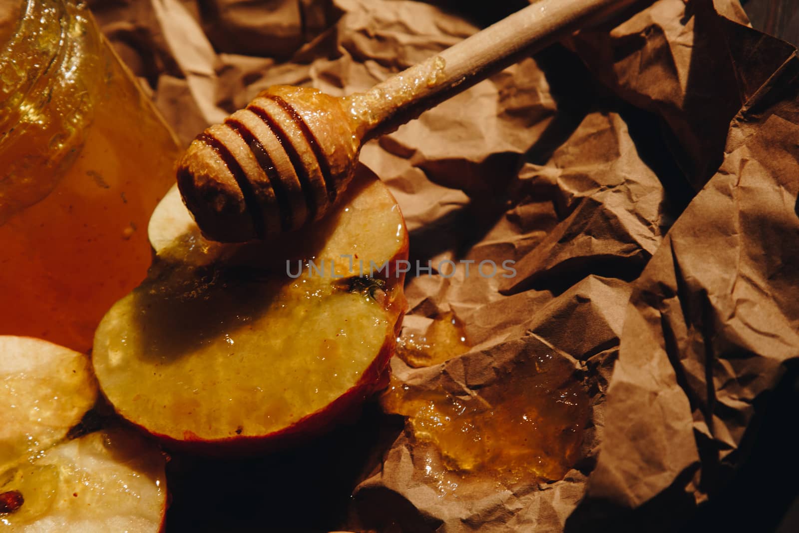 Honey with wooden honey dipper paper napkin and fruits on wooden table close up by yulaphotographer