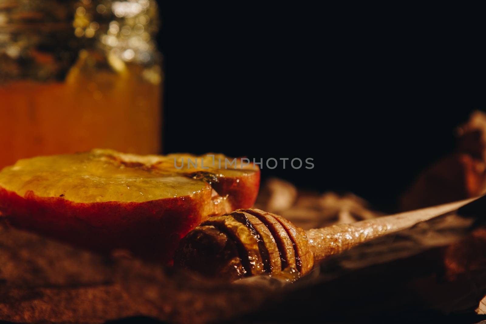 Honey with wooden honey dipper paper napkin and fruits on wooden table close up by yulaphotographer